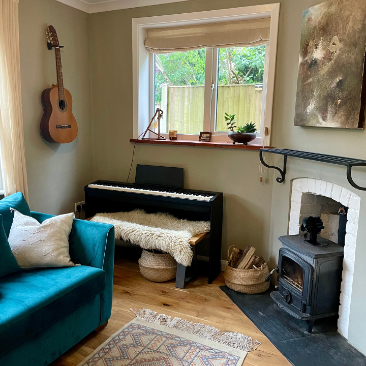 Calming music room with keyboard, teal sofa, fireplace and guitar on wall